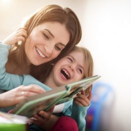 Mother and daughter reading a book and laughing